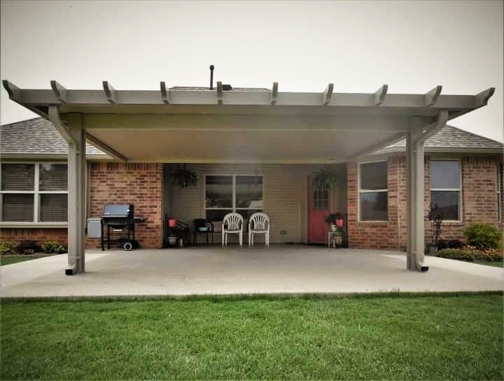 Beige solid patio cover with decorative rafter tails against a brick home