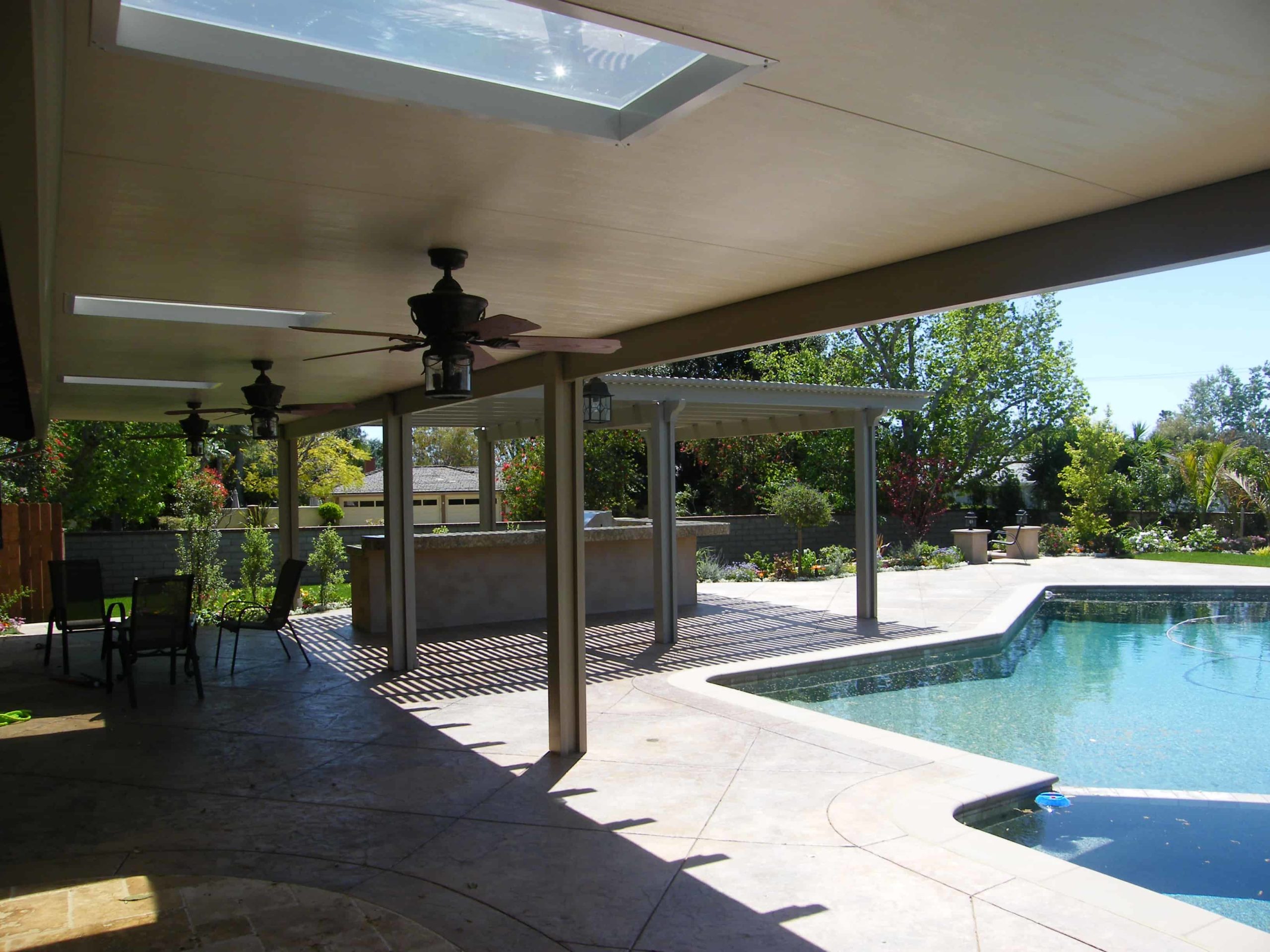 A solid cover with skylights running into an open lattice section beside a swimming pool