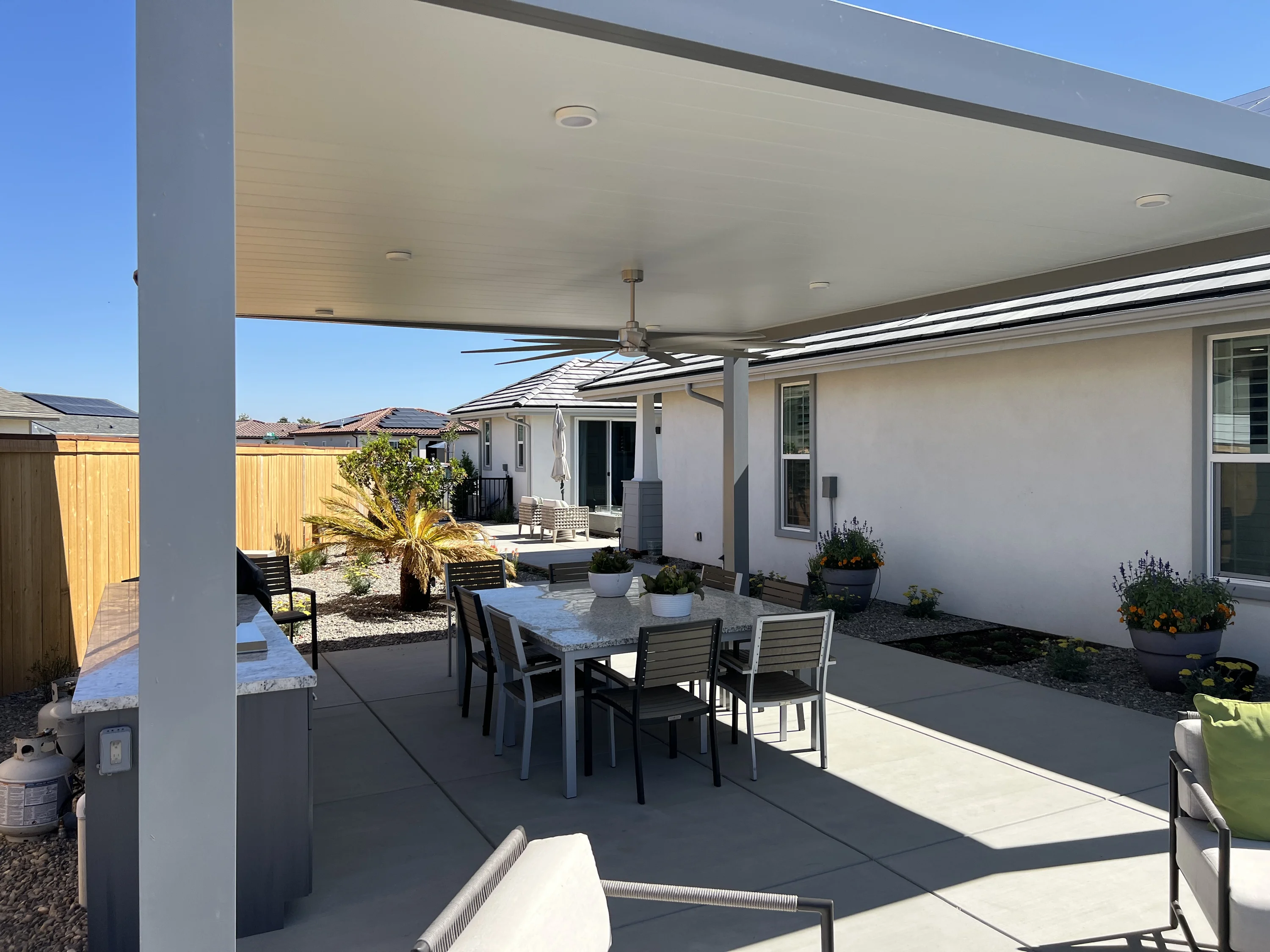 Modern white flat-panel patio cover over an outdoor dining area