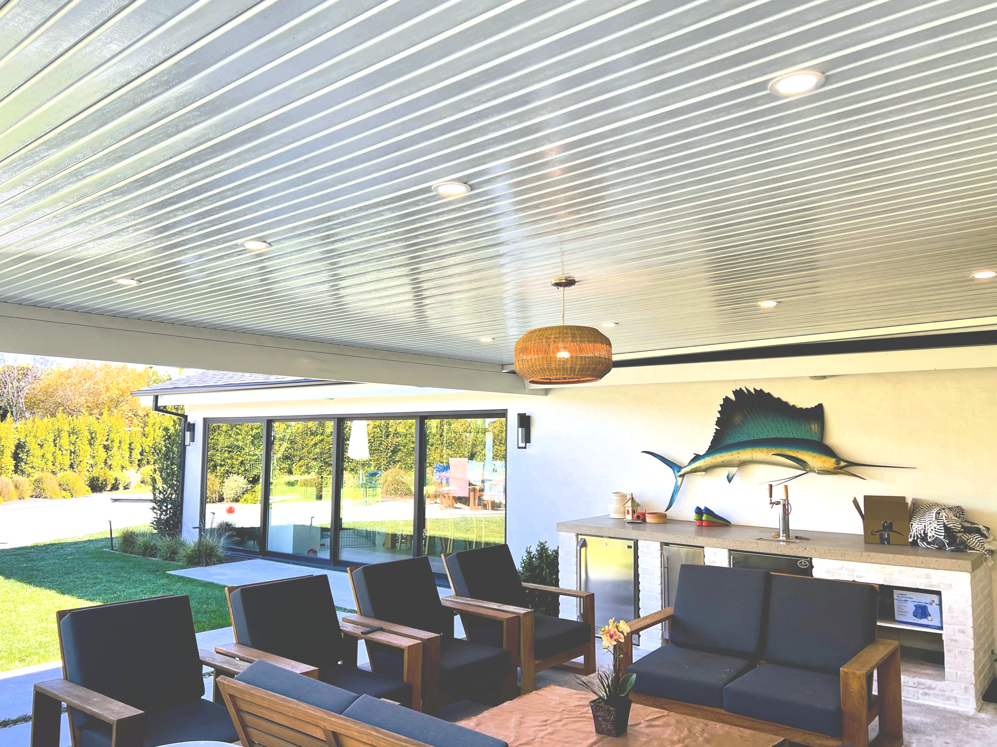 A Maxx Panel insulated cover with a white ceiling over a modern outdoor lounge and kitchen