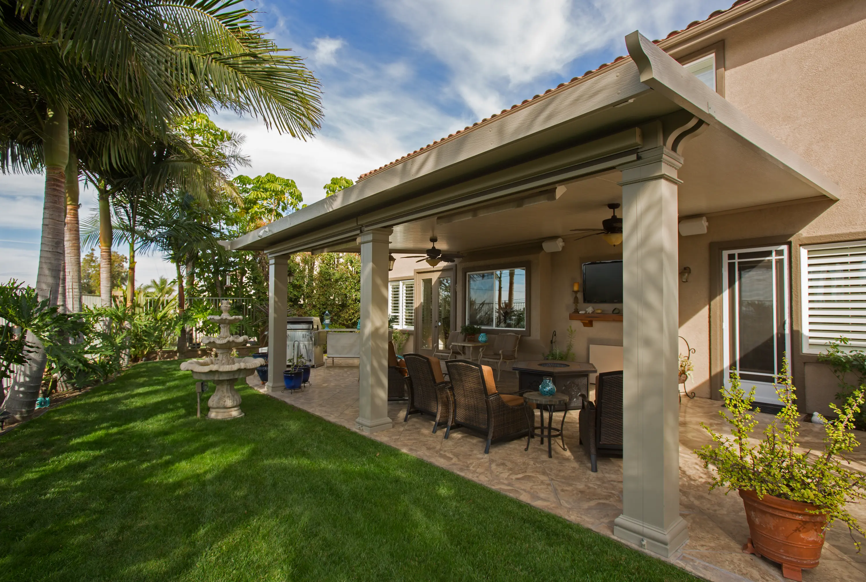 Beige solid patio cover with columns among tropical landscaping