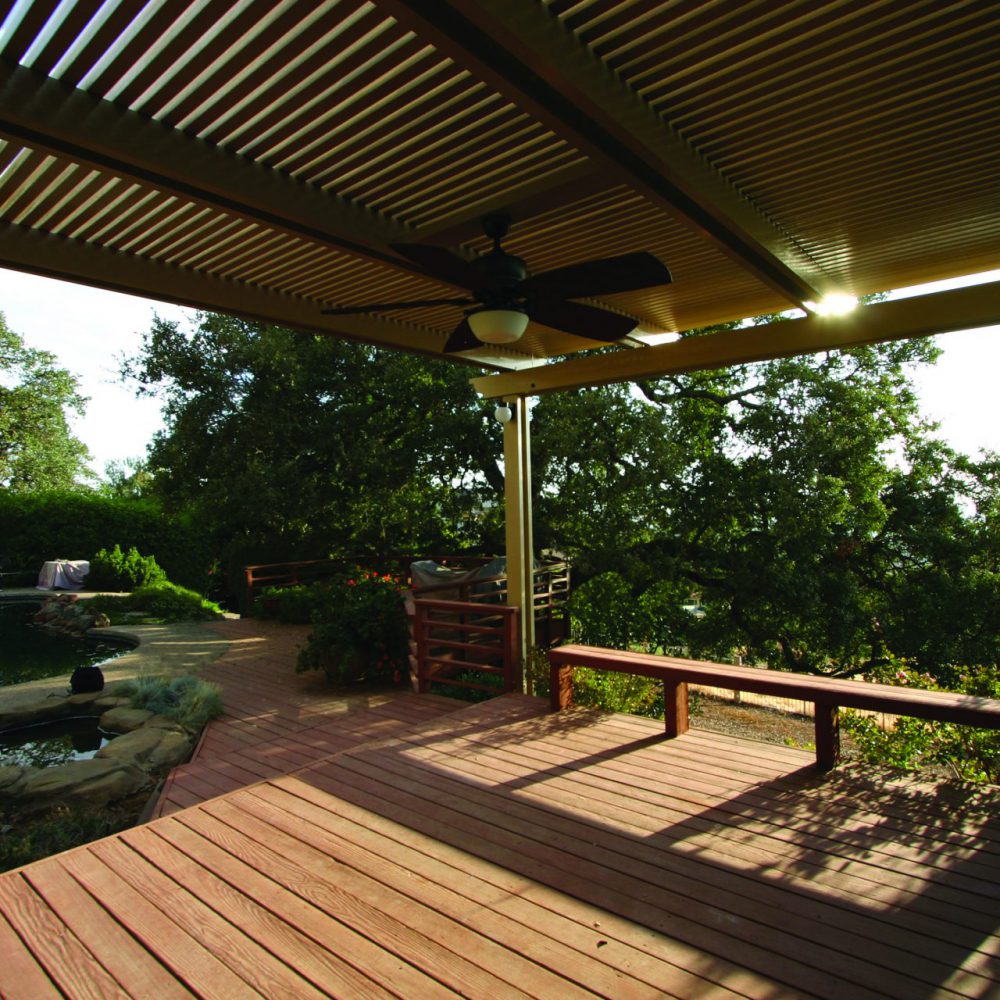 Lattice cover with ceiling fan over a wood deck beneath mature trees
