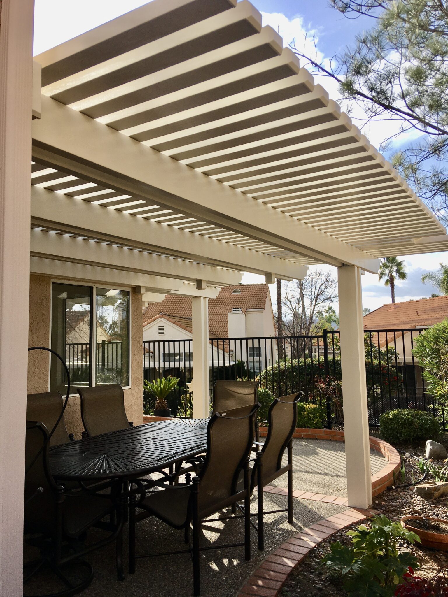 Cream open-slat lattice shading a black metal patio dining set