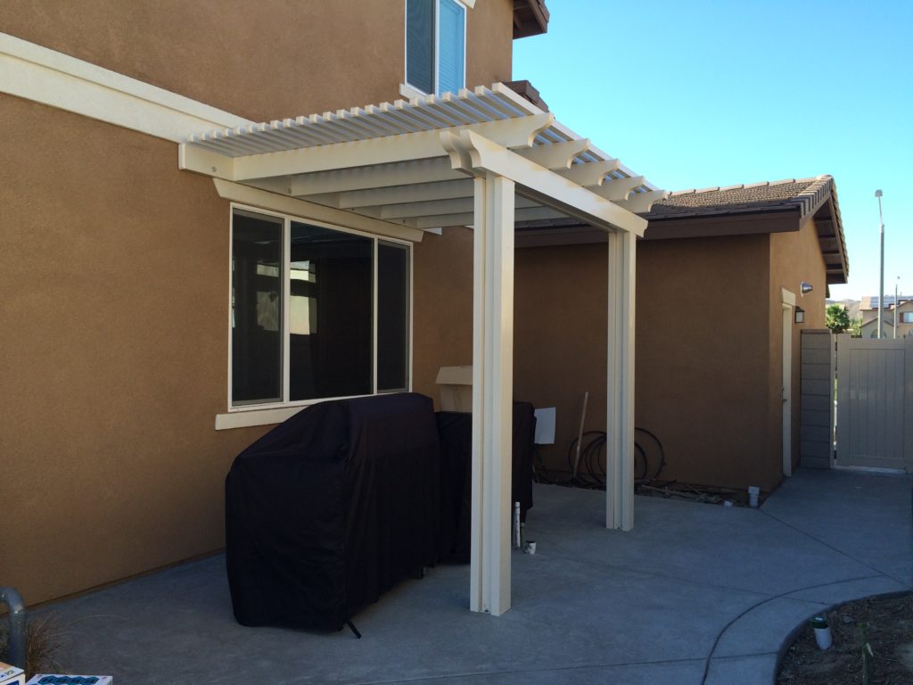 A cream lattice cover attached to a two-story stucco home over a side-yard patio