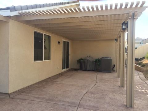 A cream lattice cover attached to a tan stucco home over a stamped-concrete patio