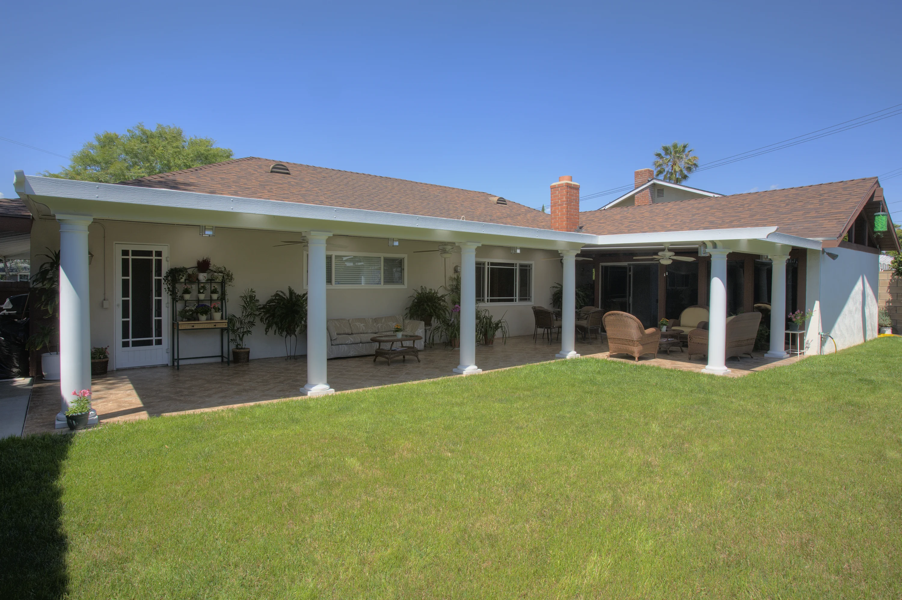 White solid patio cover with classical columns over a tiled patio