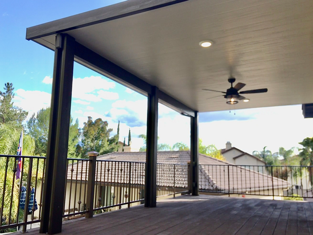 An insulated cover with recessed lighting and a ceiling fan over an elevated wood deck