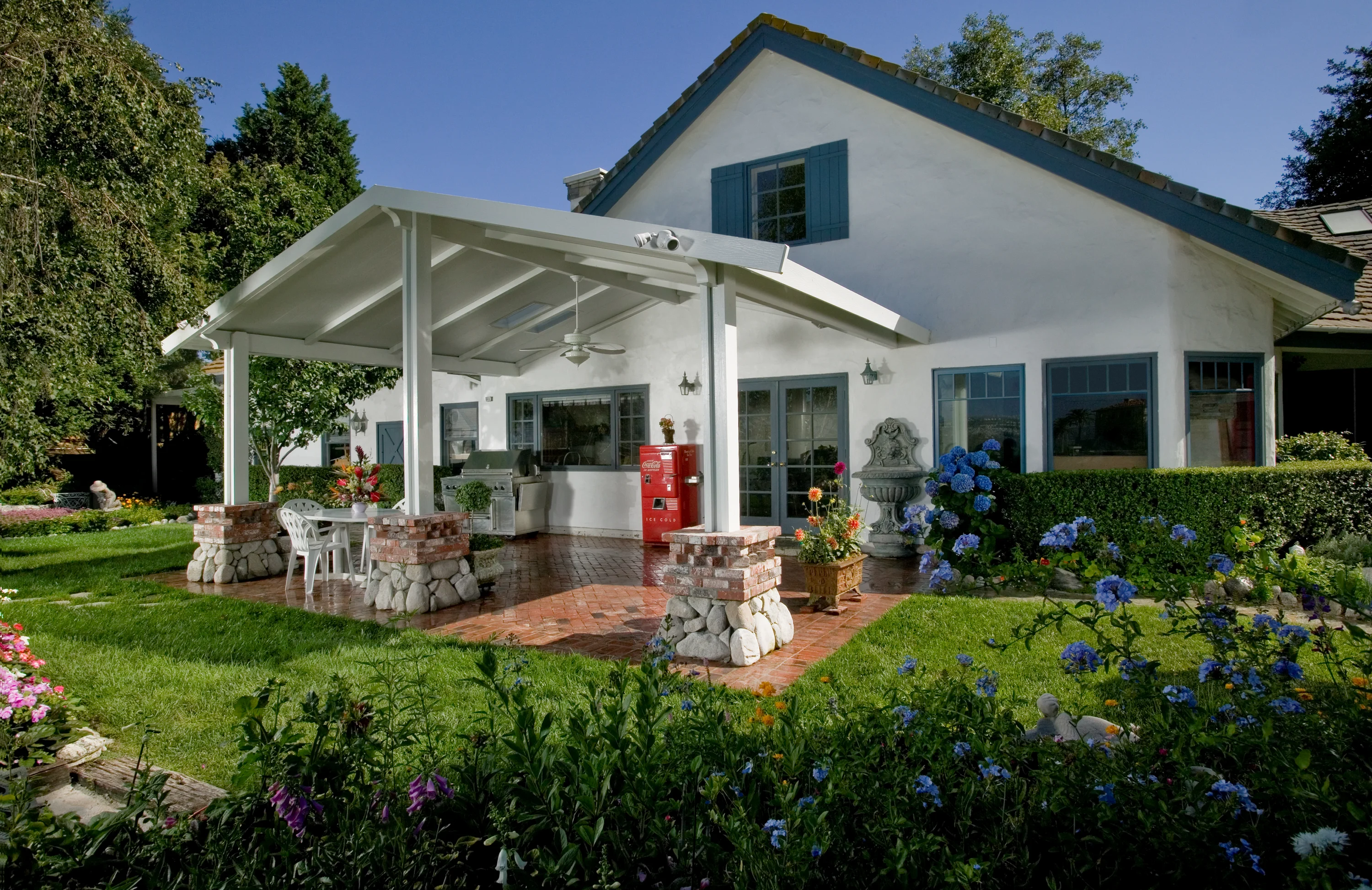 White solid gabled patio cover over a brick outdoor entertainment area