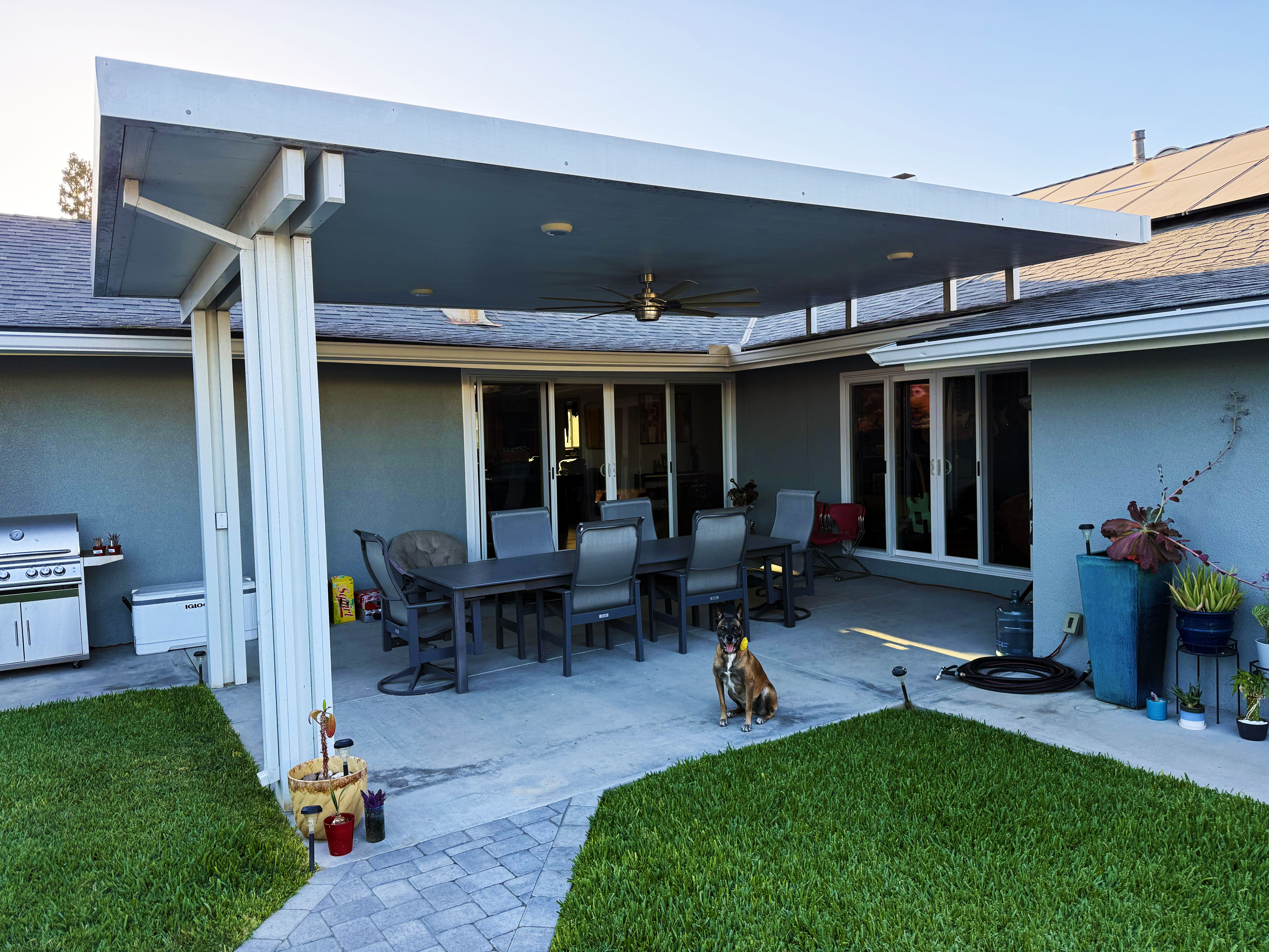 Solid panel patio cover with ceiling fan over a family dining space at golden hour